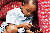 This child is very focused on his game in the mobile.
