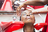 The hairdresser washes the hair of her customer after wiping.