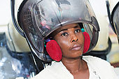 young woman placed her head under a helmet hair to dry hair.