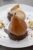 Présentation d'une assiette de dessert , une poire confite sur un fondant au chocolat.