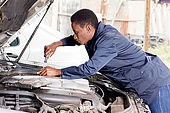 Mechanic  repairs the engine of a car in her  workshop.