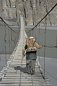 Pakistan, région de Gilgit Baltistan, Passu, un homme traverse le pont suspendu de Hosseini au dessus de la rivière Hunza