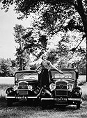Femme posant debout sur deux Peugeot 201 Berline et une Peugeot 301 Berline dans un pré en 1932.