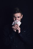 Successful poker player holds up a winning royal flush combination. Lucky gambler with playing cards on a dark background. Casino tournament winner, victory concept