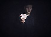 Successful poker player holds up a winning royal flush combination. Lucky gambler with playing cards on a dark background. Casino tournament winner, victory concept