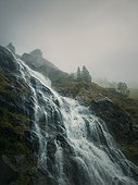 Capra waterfall on the Transfagarasan winding route of Carpathian mountains, Romania. Wonderful landscape with a tumultuous river flowing down through the cliffs in a foggy autumn morning