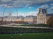 Cityscape view to the Grande Roue de Paris ferris wheel next to Louvre museum building and parisian houses, France