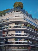 Green eco friendly building with different plants and trees growing on the balconies and on top of the roof in Paris, France. City environment, greening concept