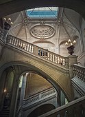 Louvre Palace architectural details of a hall with stone staircase, ornate railings and glowing vintage lamps, Paris, France