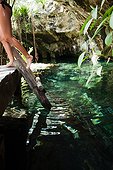 Young woman on wooden ladder, Grande Cenote, Quintana Roo, Tulum, Mexico