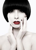 Young woman with black bob touching face