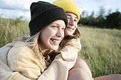 Smiling girl friends (10-11) hugging in meadow