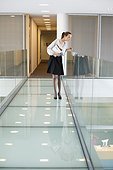 Businesswoman peeking through glass in a corridor