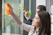 Businesswomen sticking memo notes on glass in an office
