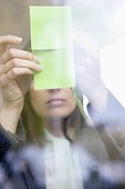 Businesswoman sticking memo notes on glass in an office