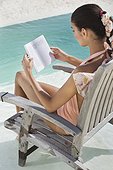 Woman sitting on a chair and reading a book on the beach