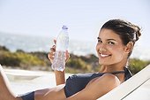 Beautiful woman holding a water bottle while sunbathing on the beach