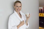 Woman in bathrobe drinking lemonade at spa