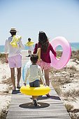 Children with their parents holding inflatable rings on a boardwalk on the beach
