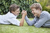 Two boys arm wrestling on grass
