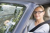 France, Paris, young woman wearing glasses, smiling, driving a car
