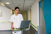 Female nurse using laptop in hospital corridor