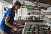 Young woman having a break playing table football in office