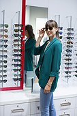 Happy young woman trying on sunglasses in optical shop
