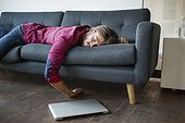 Young man sleeping on sofa with laptop