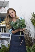 Portrait of a happy woman holding plant in her shop