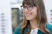 Happy young woman with glasses smiling in optical shop