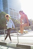 Young female athletes taking a break during exercise by railings on street