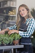 Portrait of a woman arranging potted plants in her shop