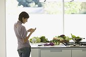 Woman preparing food and text messaging in kitchen
