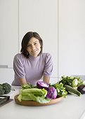 Woman posing with fresh vegetables in kitchen