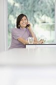 Woman having tea and talking on cell phone