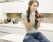 Woman eating chocolate cake in kitchen