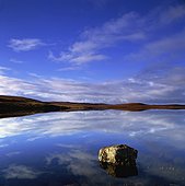 Clouds in blue sky reflected in still lake