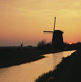 Silhouette of windmill and river in rural landscape