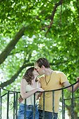 Couple hugging and kissing near railing outdoors