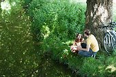 Couple with bicycles sitting on riverbank together