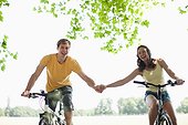 Couple riding bicycles and holding hands