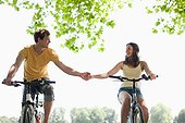 Couple riding bicycles and holding hands