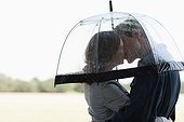 Couple in rain kissing underneath umbrella