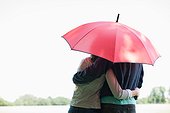 Couple hugging underneath red umbrella