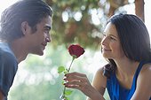 Smiling couple outdoors with red rose