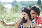 Smiling couple taking self-portrait with cell phone outdoors