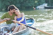 Couple rowing rowboat together on lake