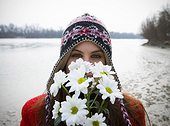 Young woman outdoors holding flowers up to face, portrait