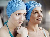 Two women wearing swimming caps and bathing suits, close-up